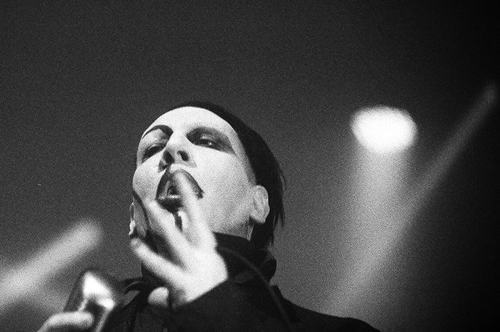 Singer performing on stage in dramatic lighting.