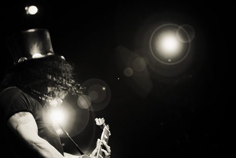 Guitarist performing on stage with spotlight.