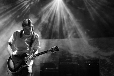 Guitarist performing under dramatic stage lighting.
