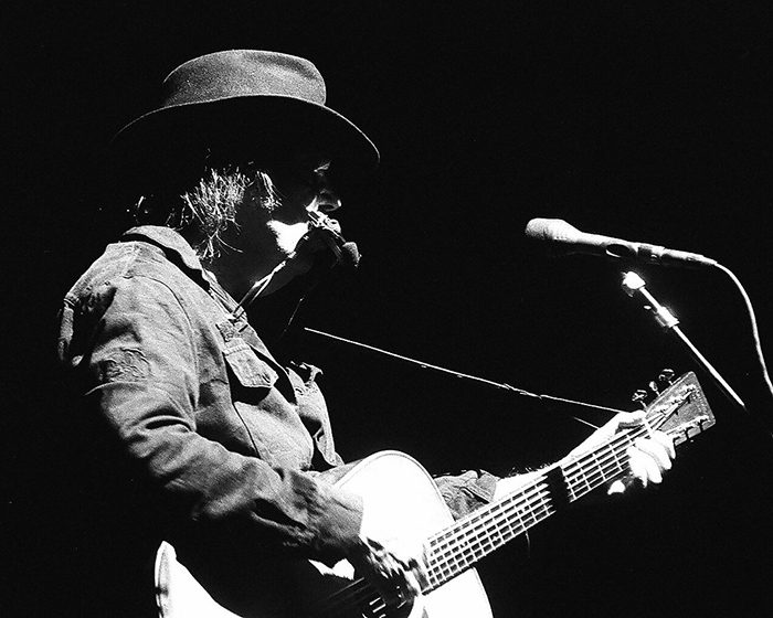 Musician playing guitar on stage in silhouette.