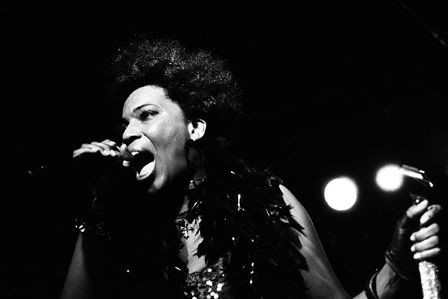 Singer passionately performing on stage, monochrome.