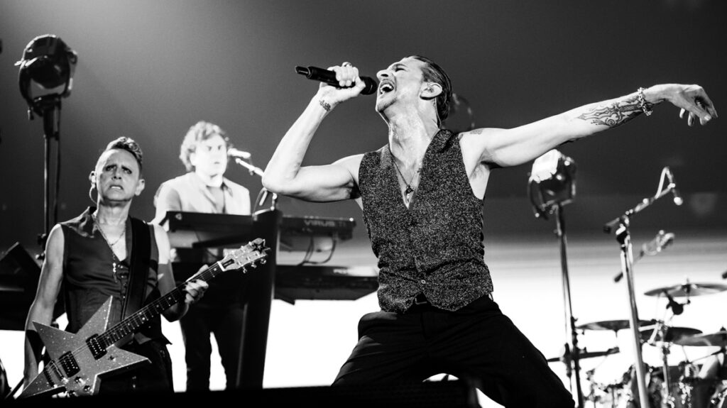 Band performing energetically on stage, black and white.