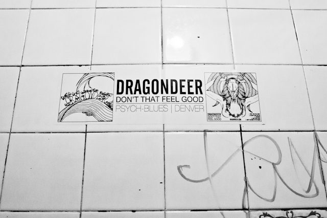 Band poster on tiled wall with graffiti.