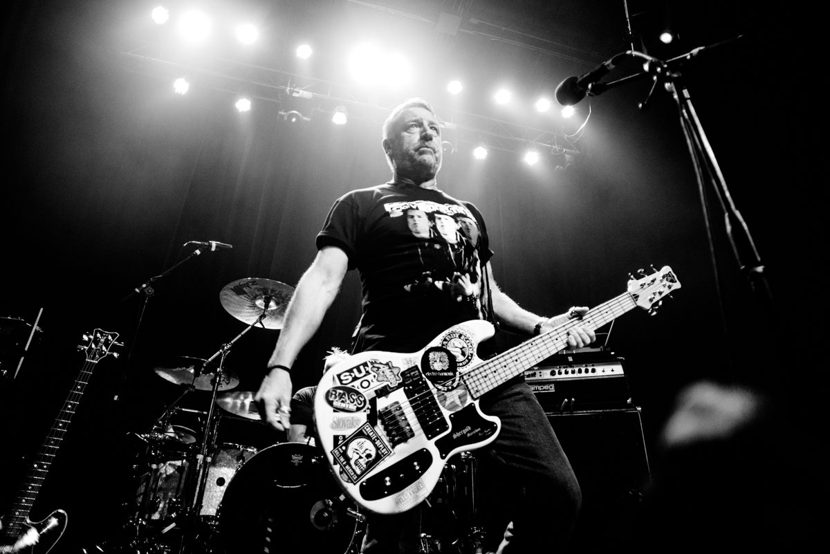 Musician playing guitar on stage, black and white.