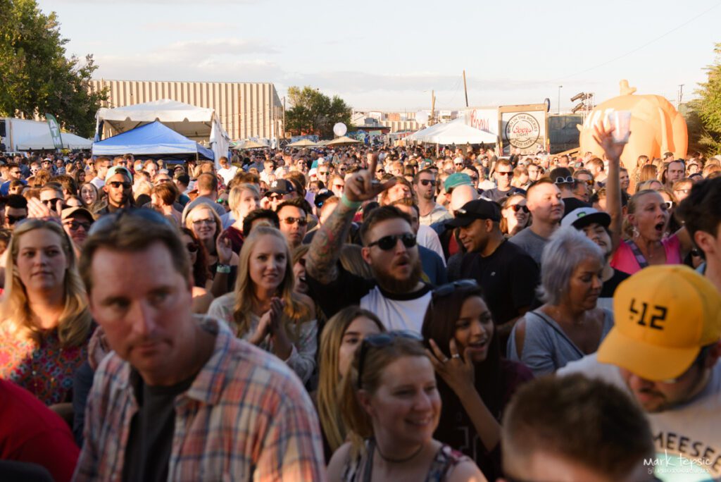 Crowd enjoying outdoor festival under clear sky.