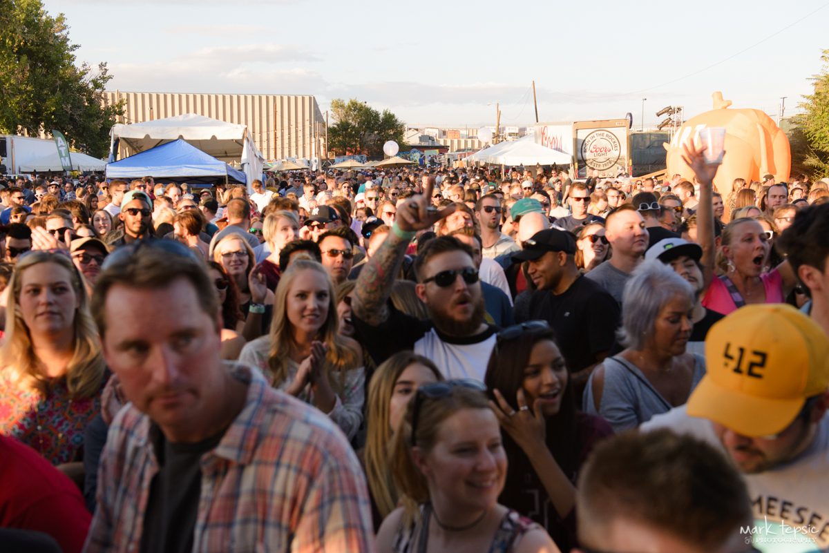 Crowd enjoying outdoor festival under clear sky.
