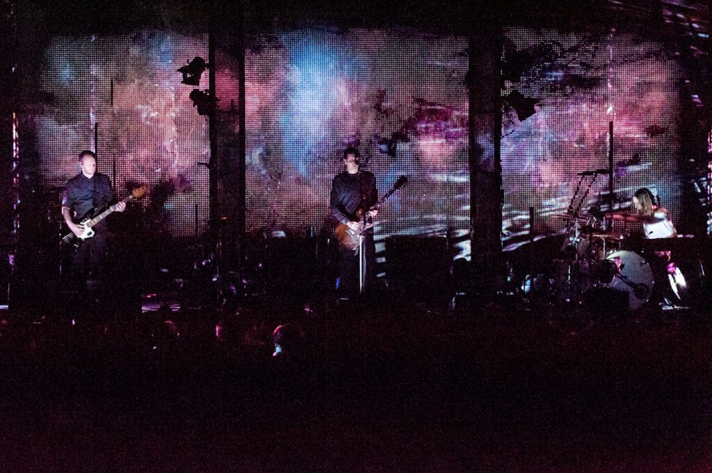 Band performing on stage with colorful backdrop.