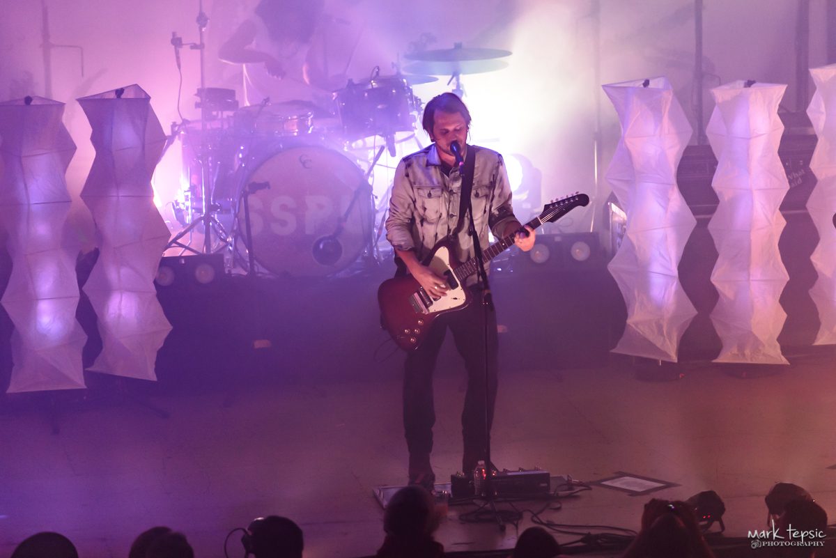Musician performing on stage with guitar.
