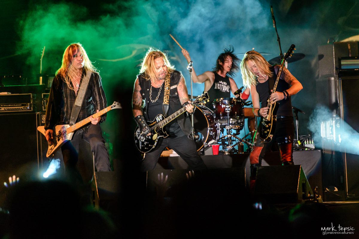 Rock band performing energetically on stage.