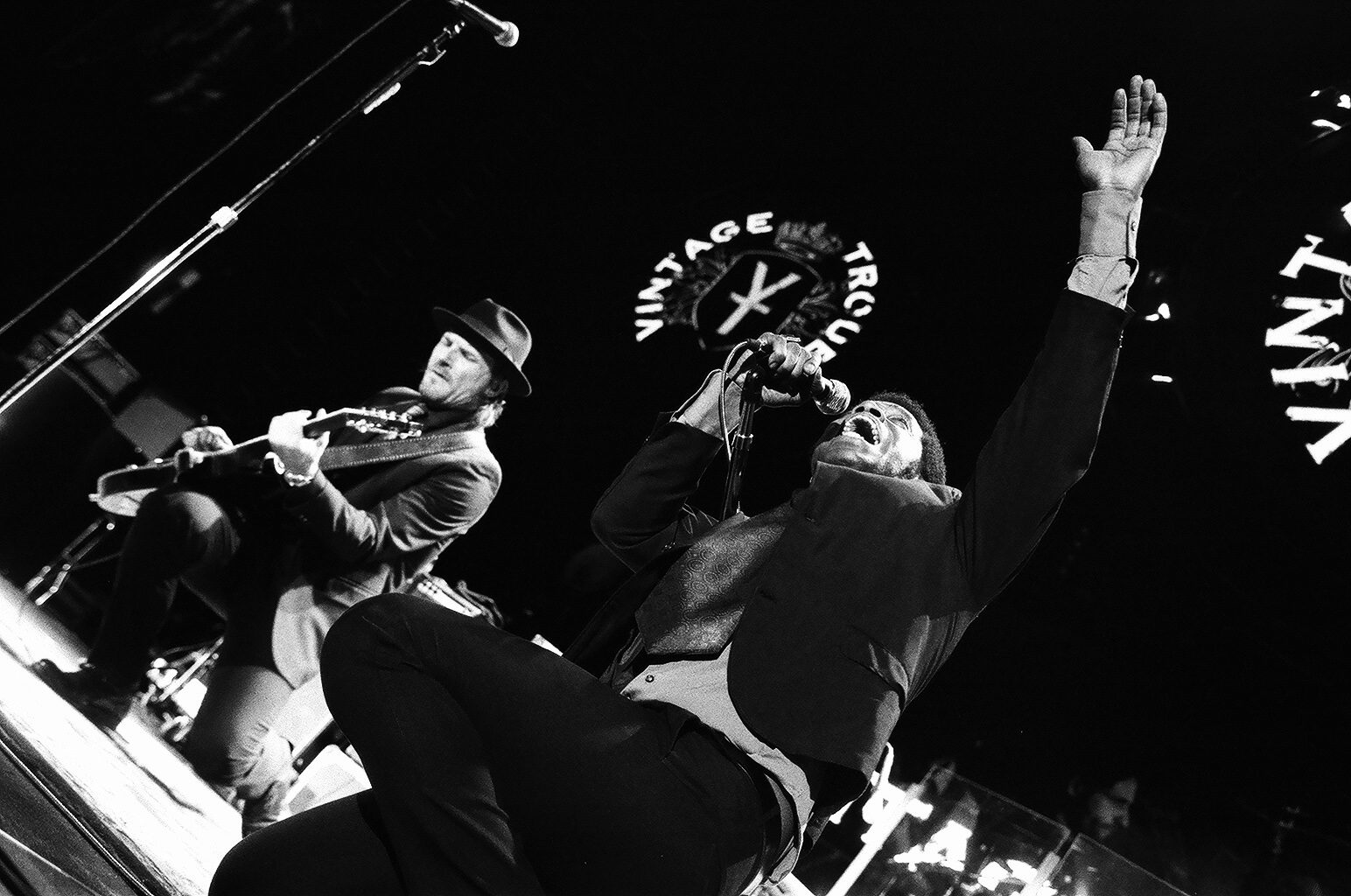 Musicians performing energetically on stage in black and white.