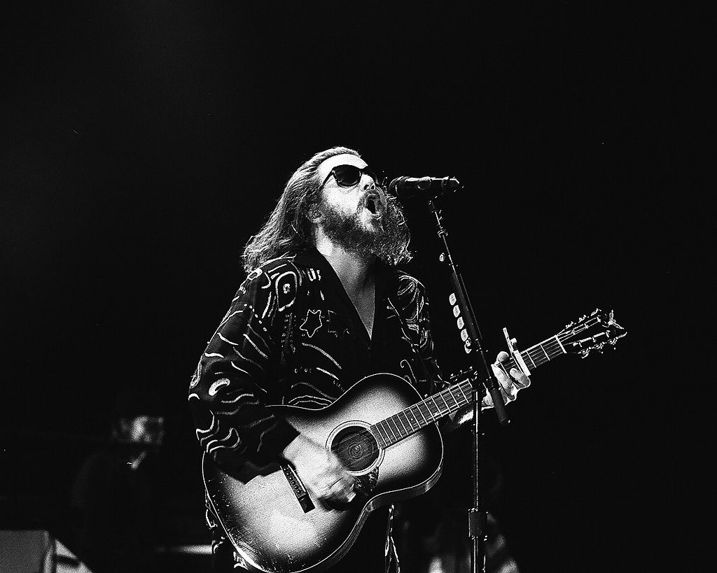 Musician performing with guitar on stage.