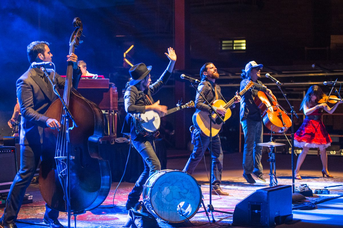 Band performing energetically on stage with instruments.