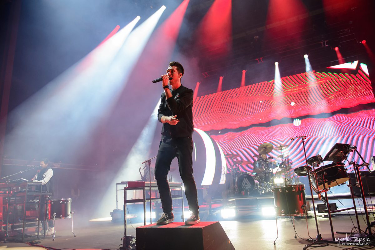 Band performing live on stage with lights.