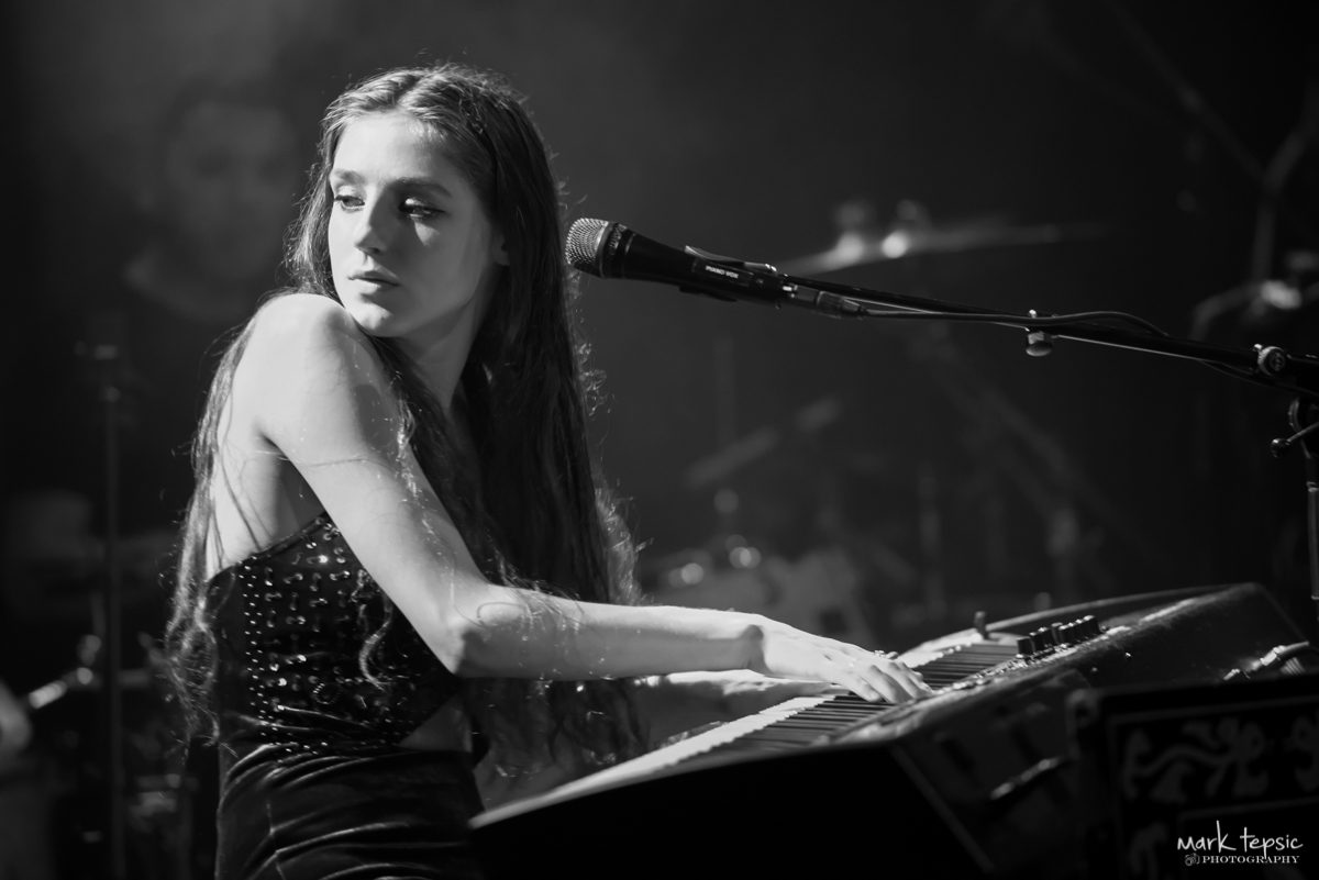 Young woman playing keyboard on stage.