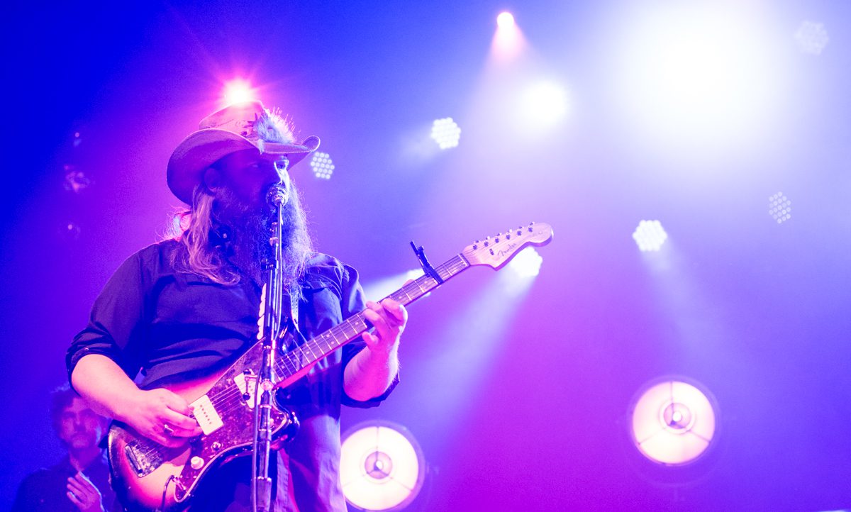 Guitarist performing on stage with vibrant lights.