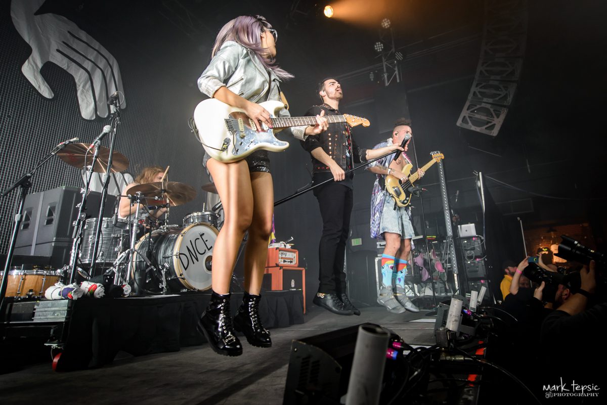 Band performing energetically on stage with instruments.