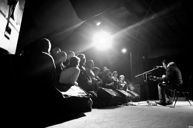 Musician performing on stage to audience.