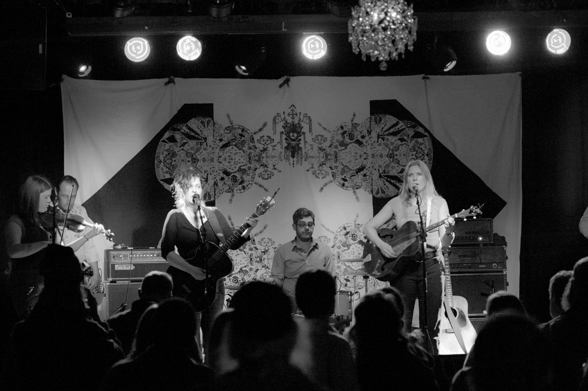 Band performing on stage with audience watching.