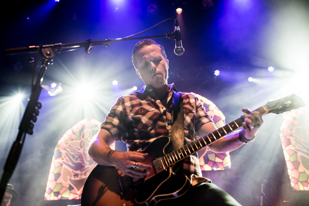 Guitarist performing under colorful stage lights.