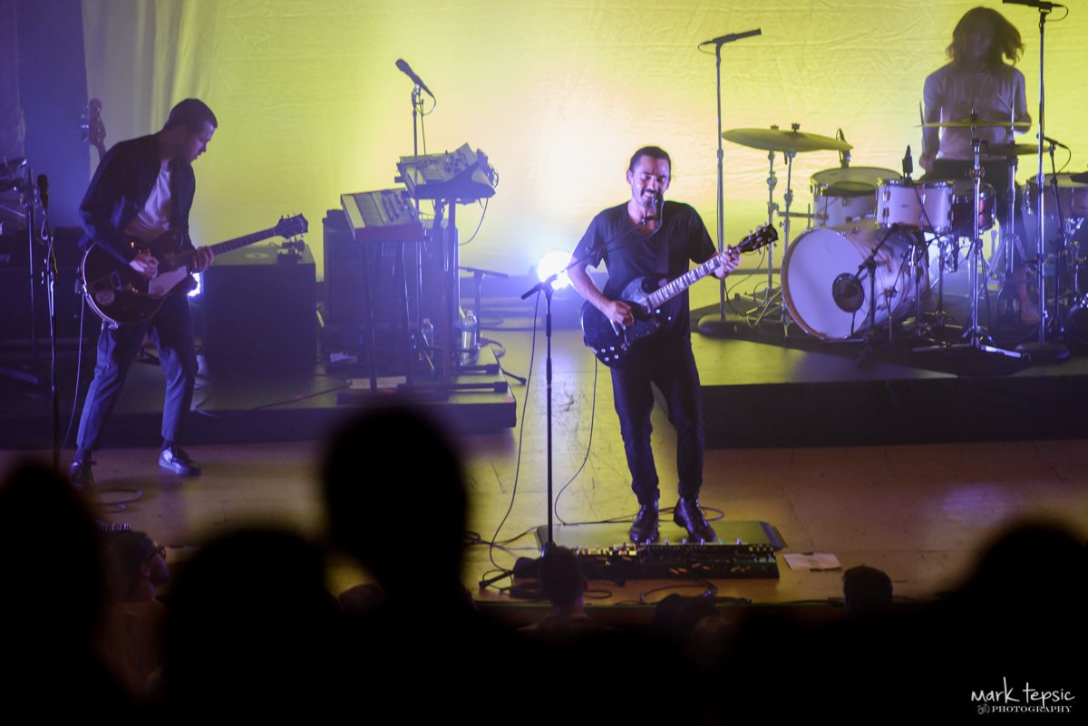 Band performing on stage with colorful lighting.