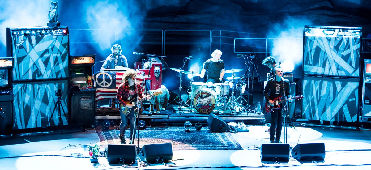 Band performing on stage with colorful lights.