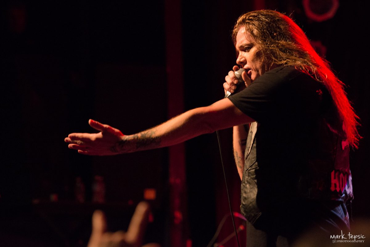 Singer performing passionately on stage with microphone.