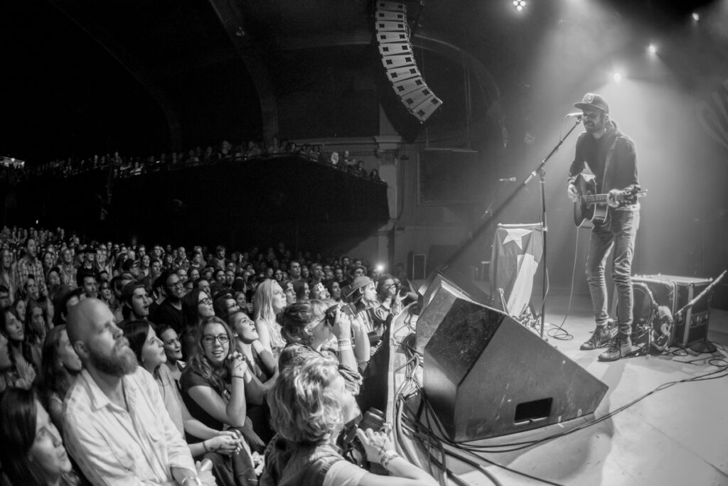Musician performing on stage to enthusiastic audience.