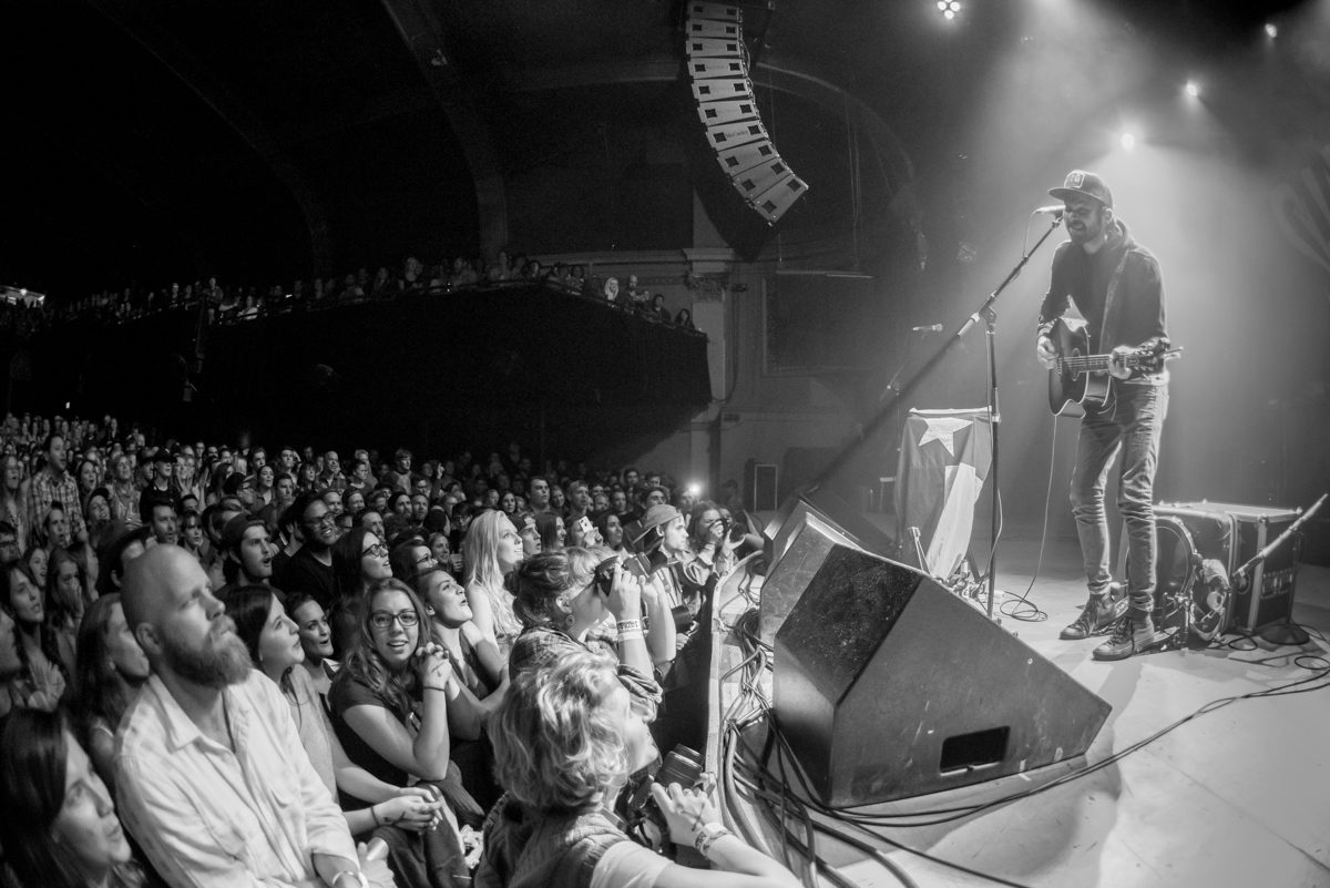 Musician performing on stage to enthusiastic audience.
