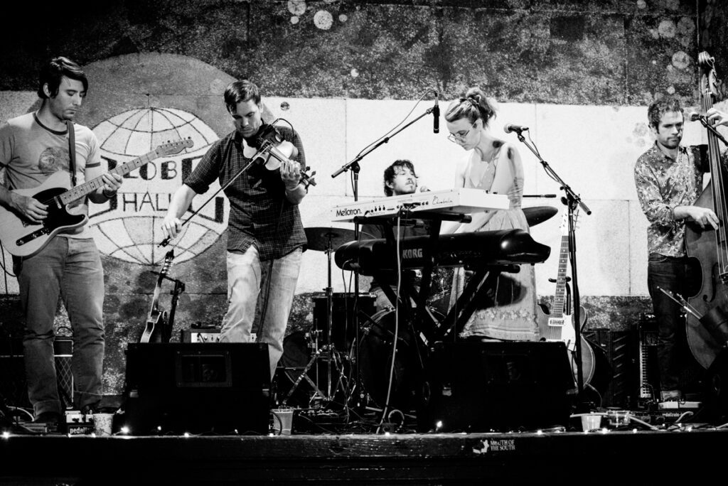 Band performing on stage with various instruments.