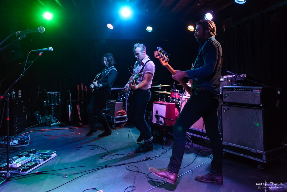 Band performing live on stage with instruments.