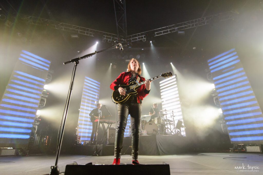 Guitarist performing on stage with bright lights.