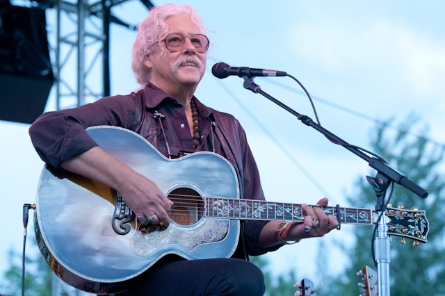 Musician playing acoustic guitar on stage.