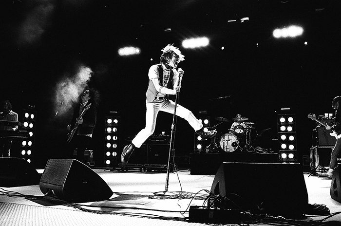 Rock band performing energetically on stage.