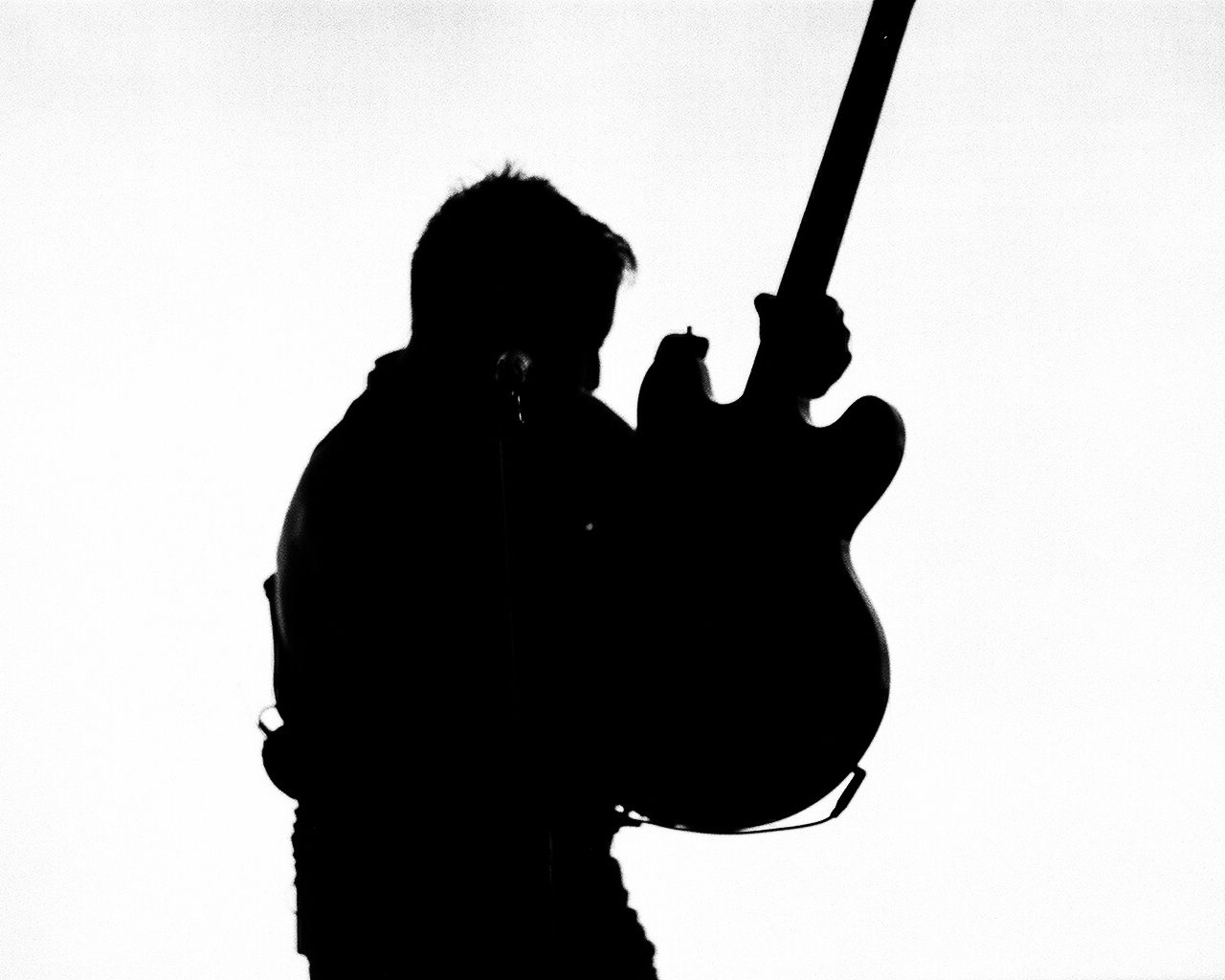 Silhouette of guitarist holding an electric guitar.