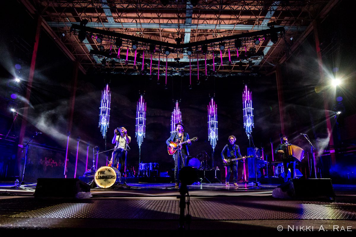 Band performing on stage with vibrant lights.