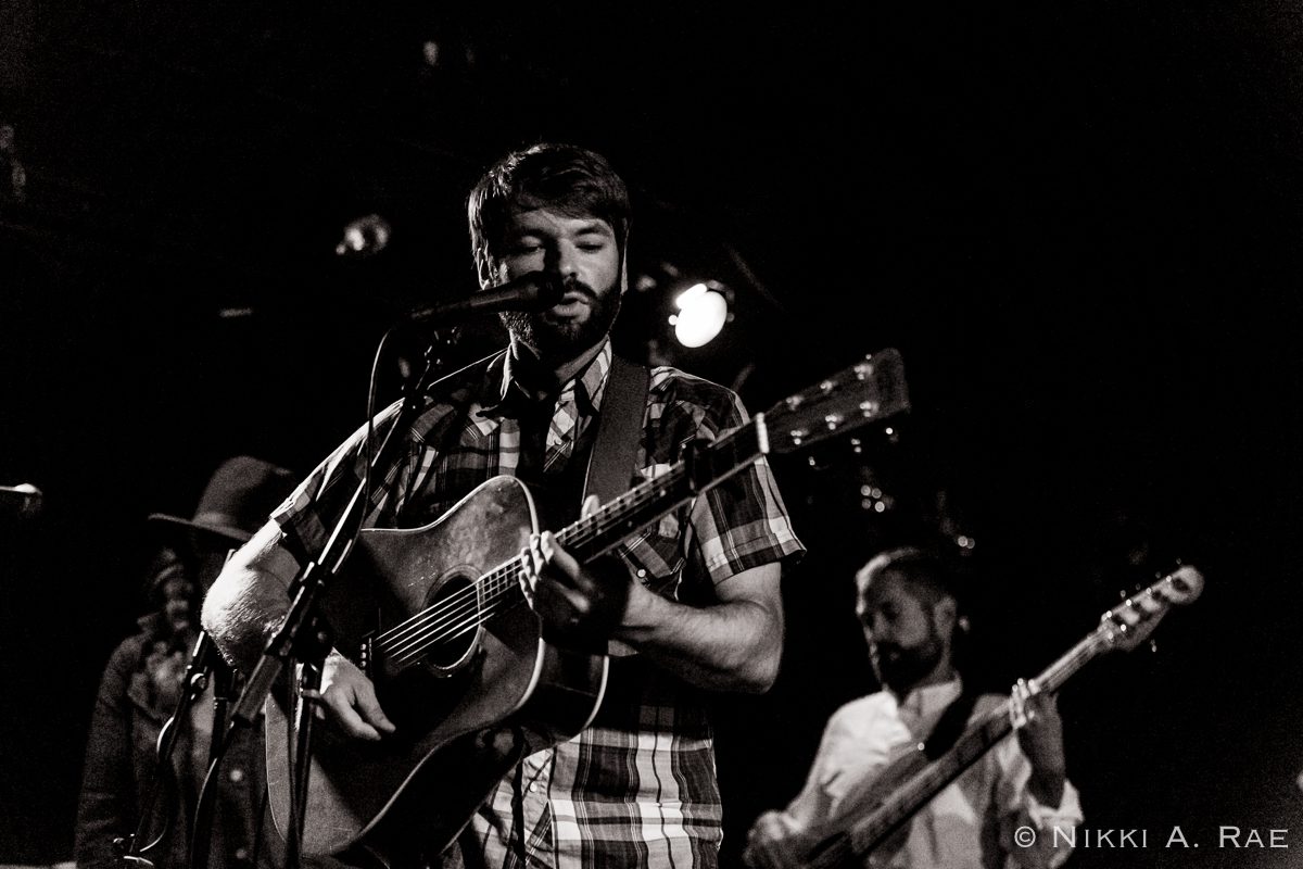 Musician performing on stage with guitar.