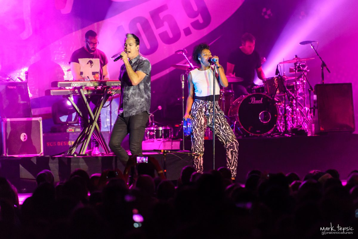 Singers performing on stage with band.