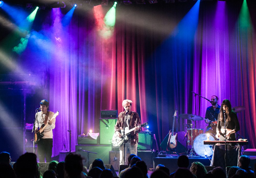 Band performing on stage with colorful lights.