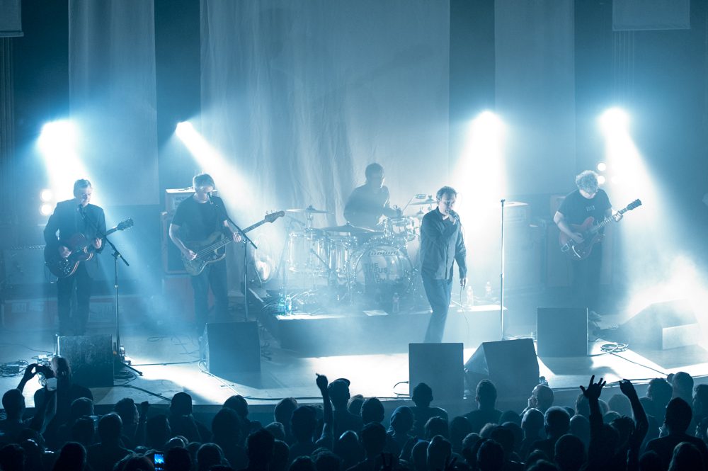 Band performing on stage with bright lights.