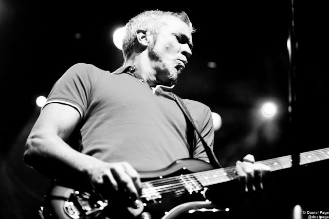 Guitarist performing on stage in black and white.