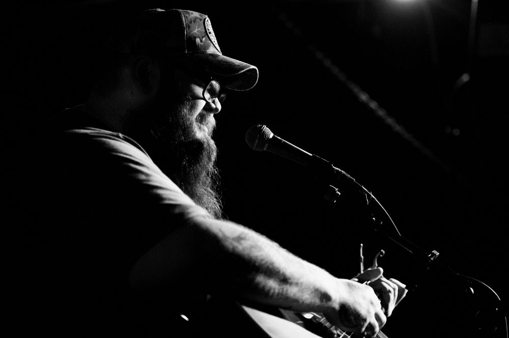 Singer performing on stage with guitar.