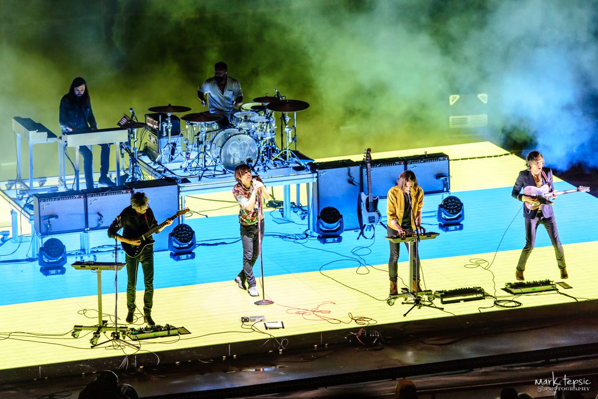 Band performing on stage with colorful lighting.