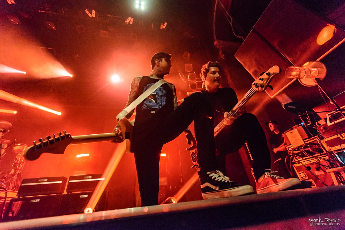 Musicians performing energetically on stage with guitars.