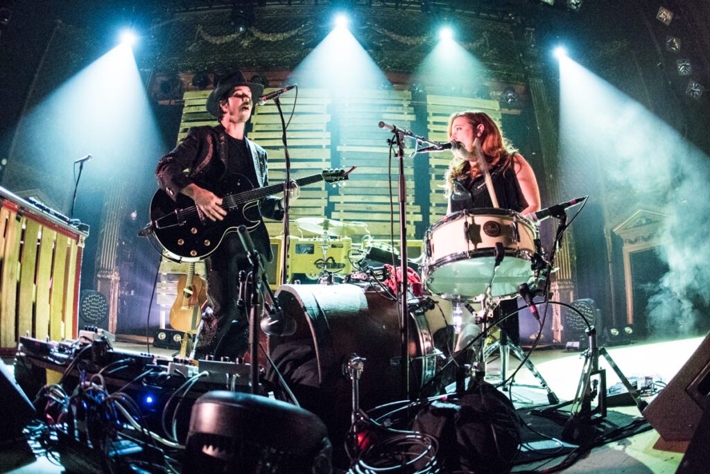 Musicians performing energetically on stage with instruments.