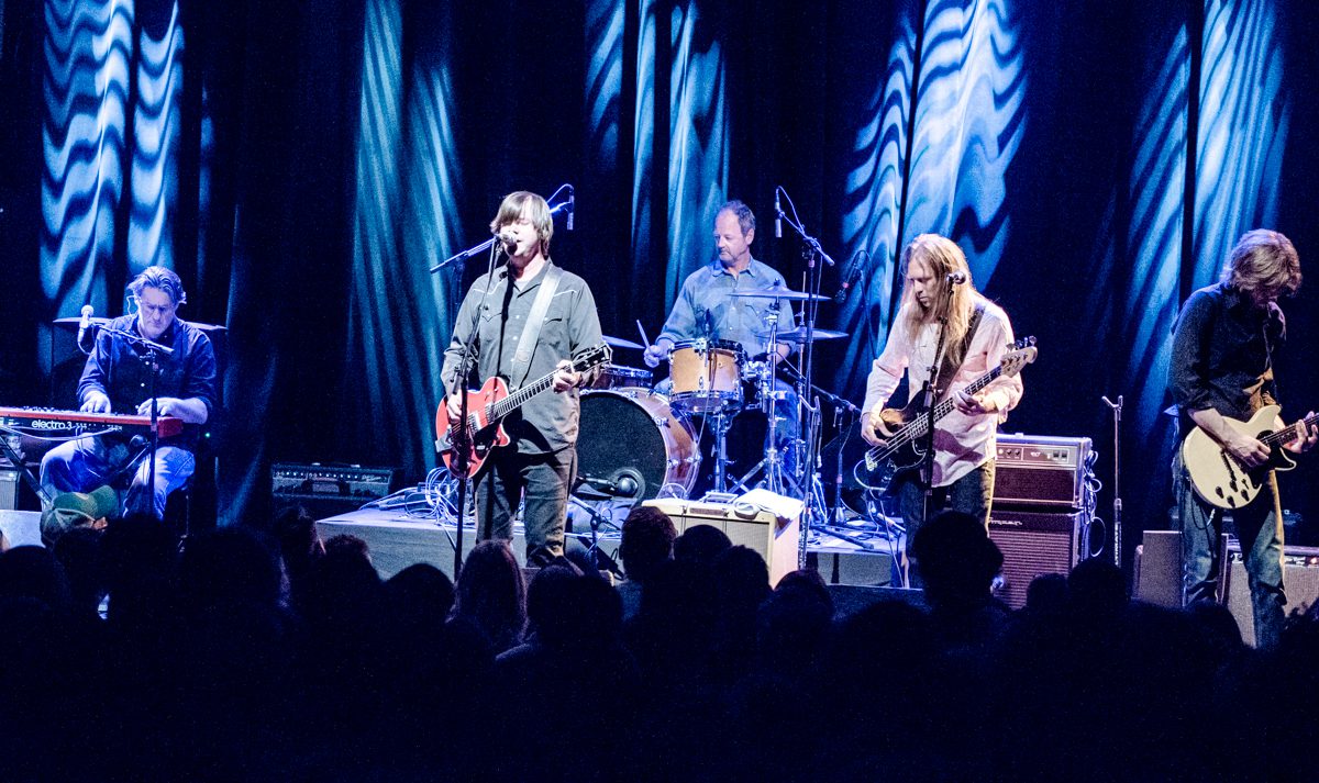 Band performing live on stage with instruments.