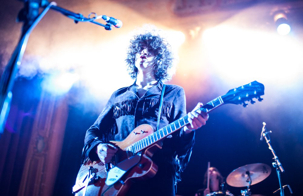 Musician performing with guitar under bright lights.