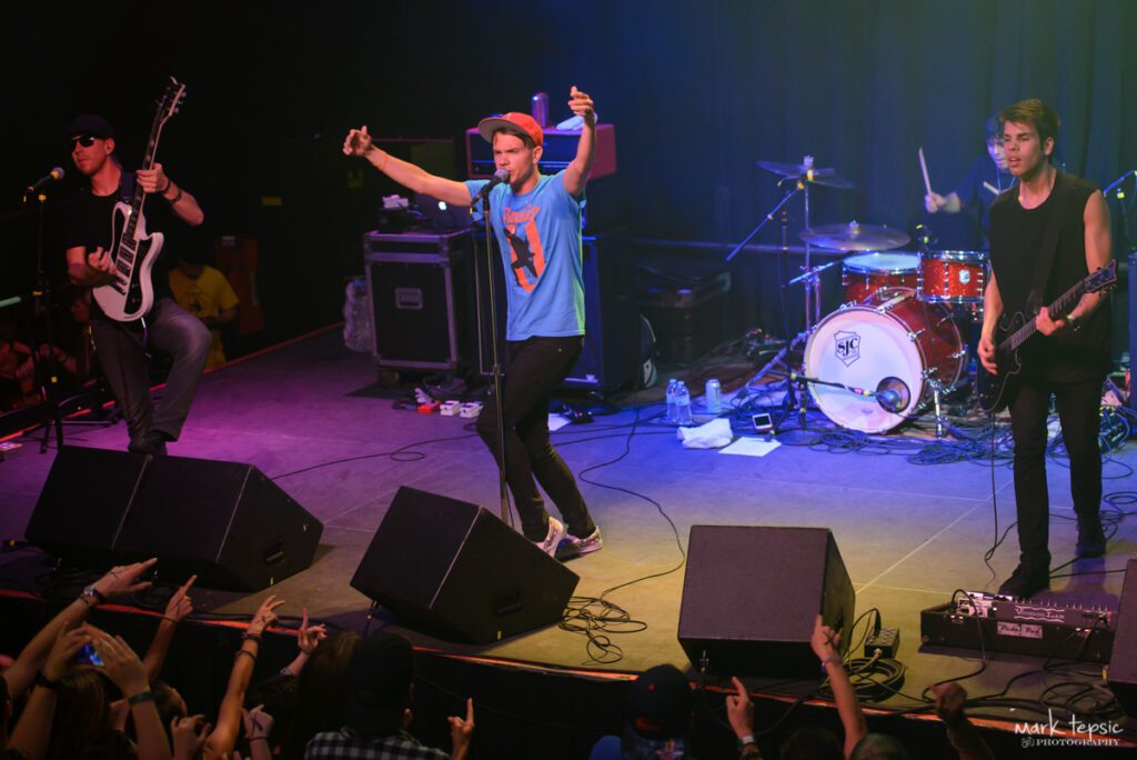 Band performing live on stage with instruments.