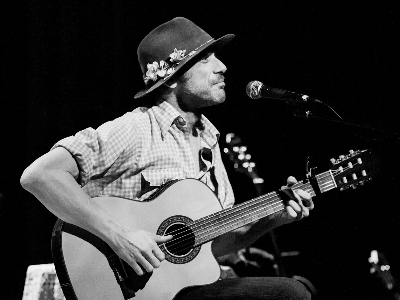 Musician playing guitar and singing on stage.
