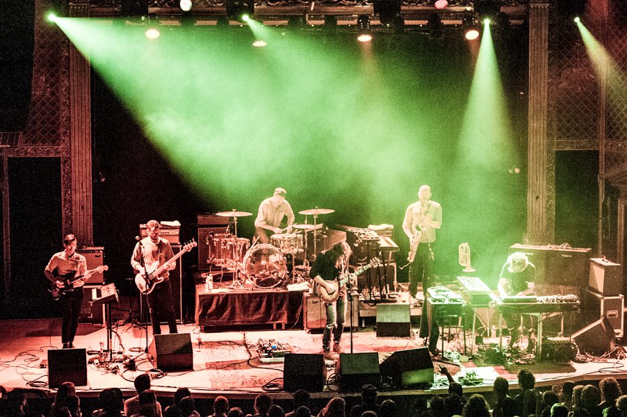 Band performing on stage with green lighting.