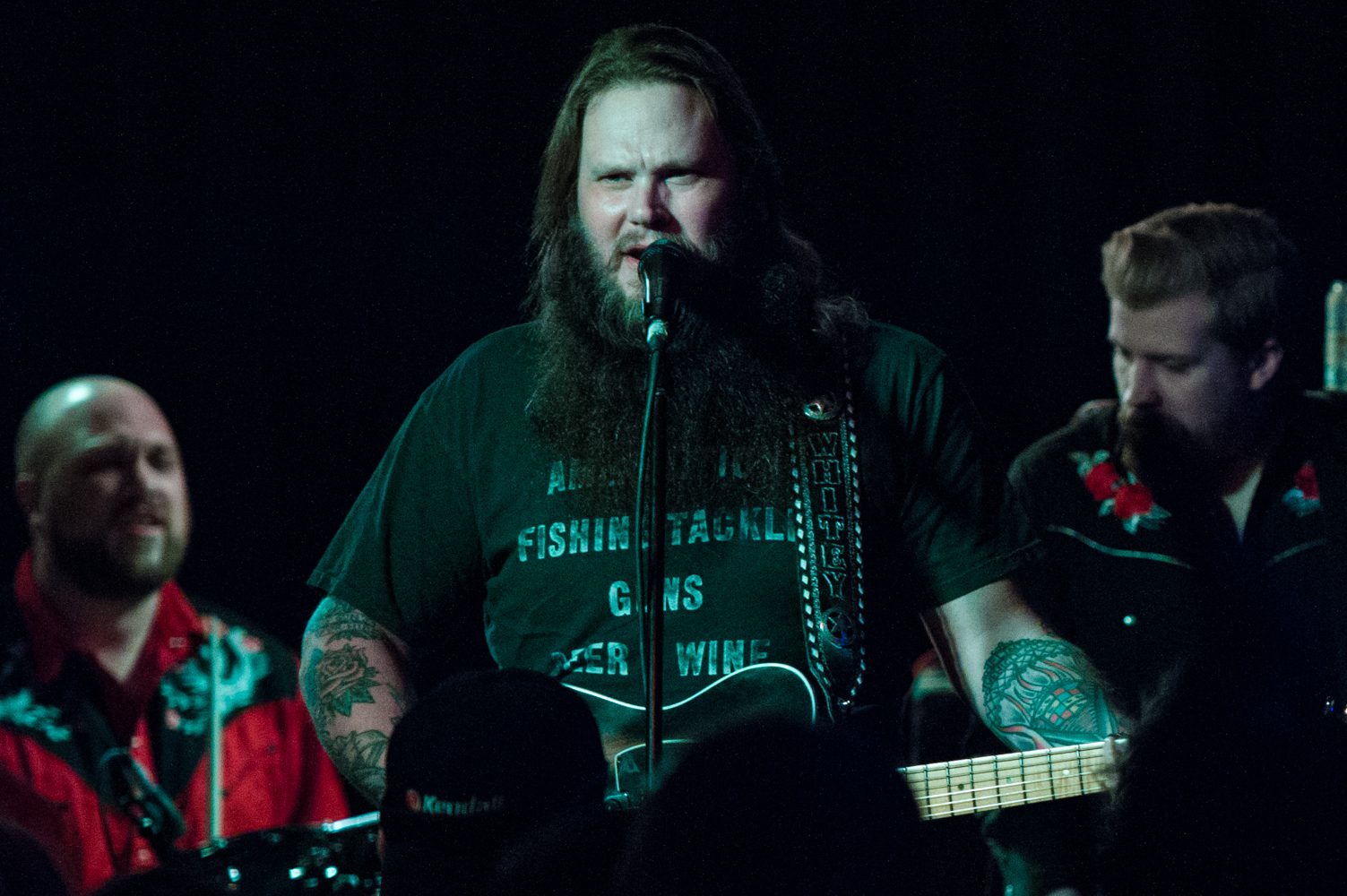 Musician performing with guitar on stage.